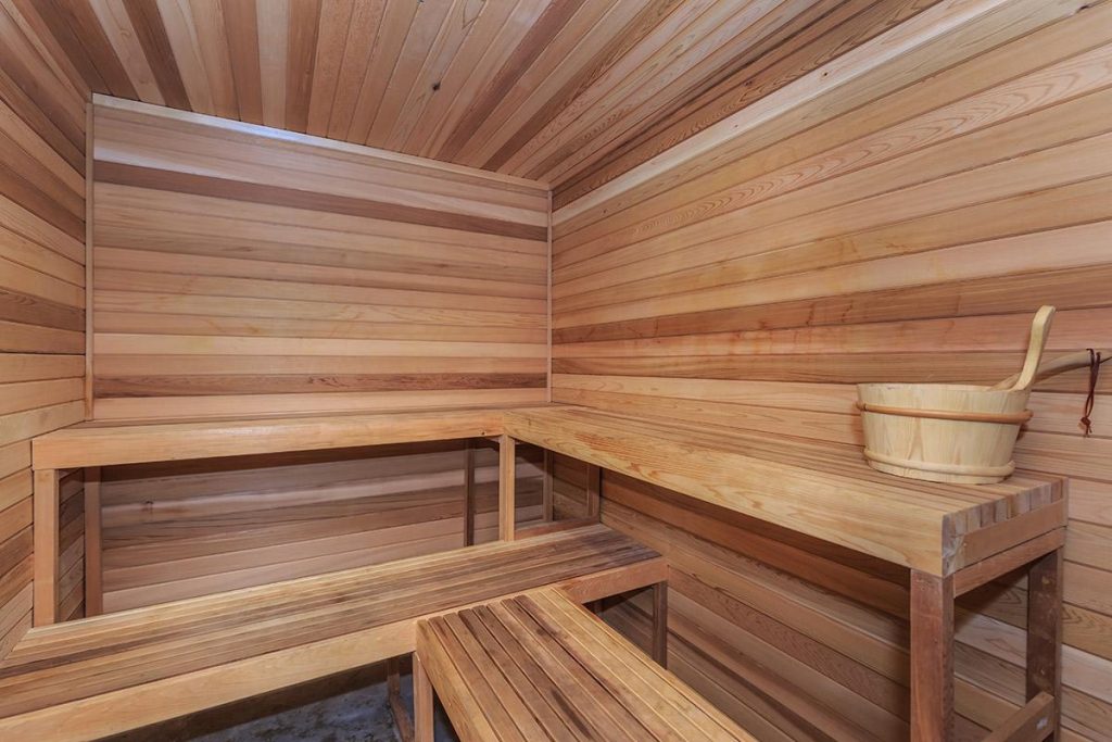 A cozy sauna room with wooden benches and a bucket, perfect for unwinding after a long day in Hollywood CA apartments.