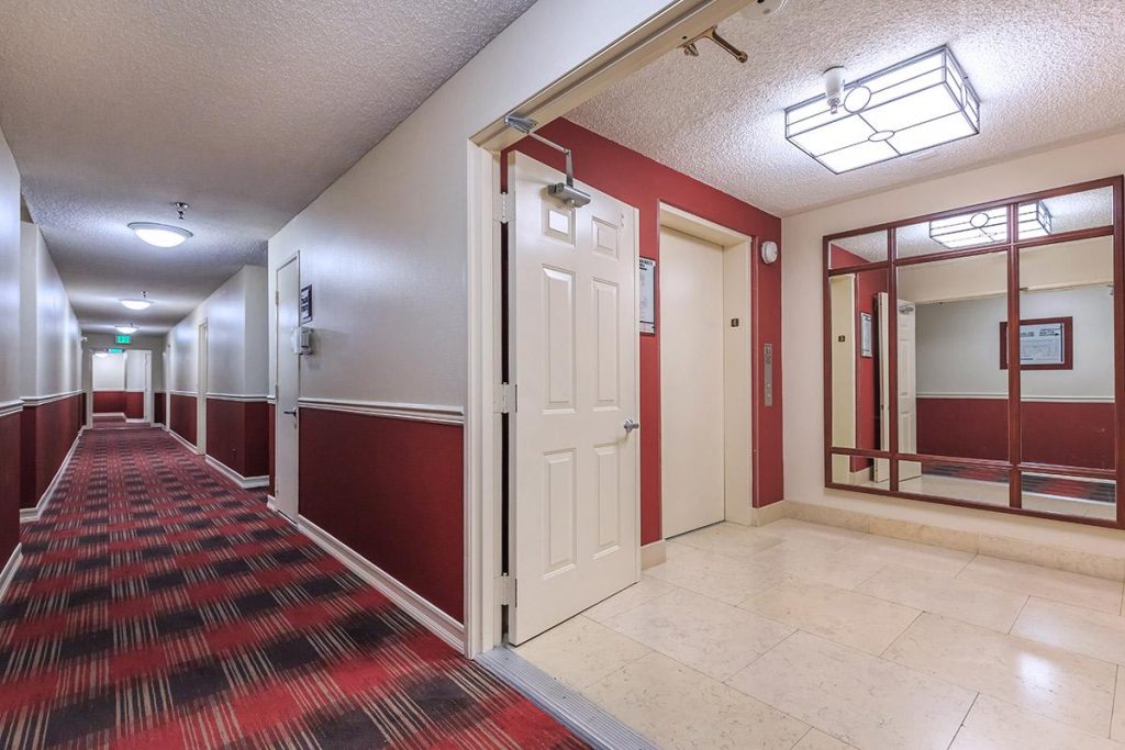 A hallway in a hotel with red carpet and red walls, situated in Hollywood CA.