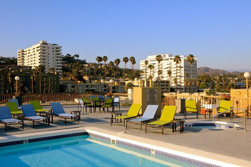 A rooftop pool with lounge chairs and a view of the city, located in apartments for rent in Hollywood CA.