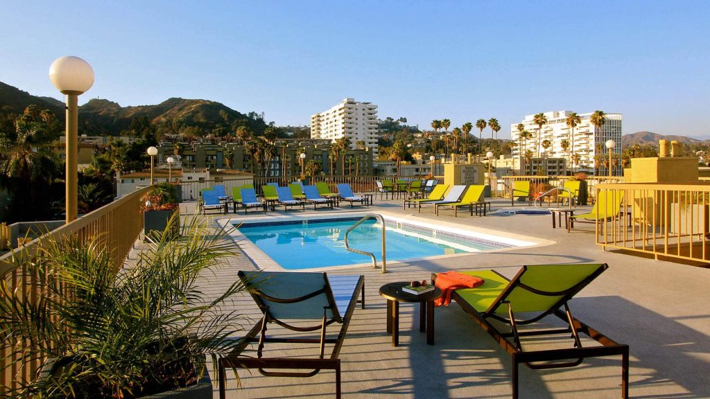 Apartments with a rooftop pool that offers lounge chairs and a stunning view of the mountains in Hollywood, CA.