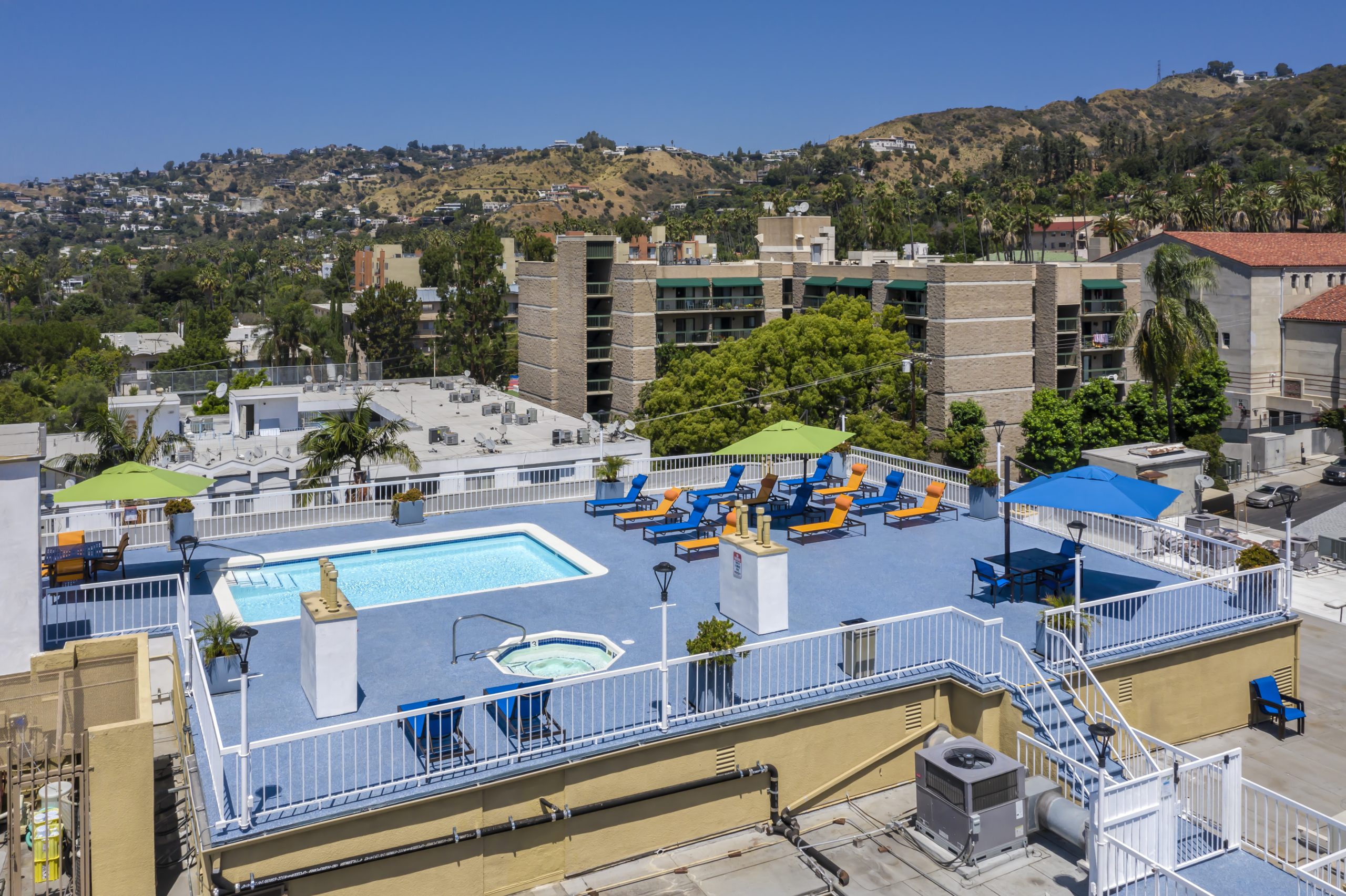 A rooftop pool with lounge chairs offering breathtaking views of the Hollywood hills.