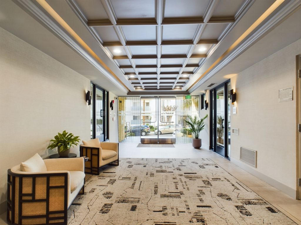 A hallway in an apartment building with a rug and chairs, providing a glimpse into the comfortable living available in apartments for rent in Hollywood CA.