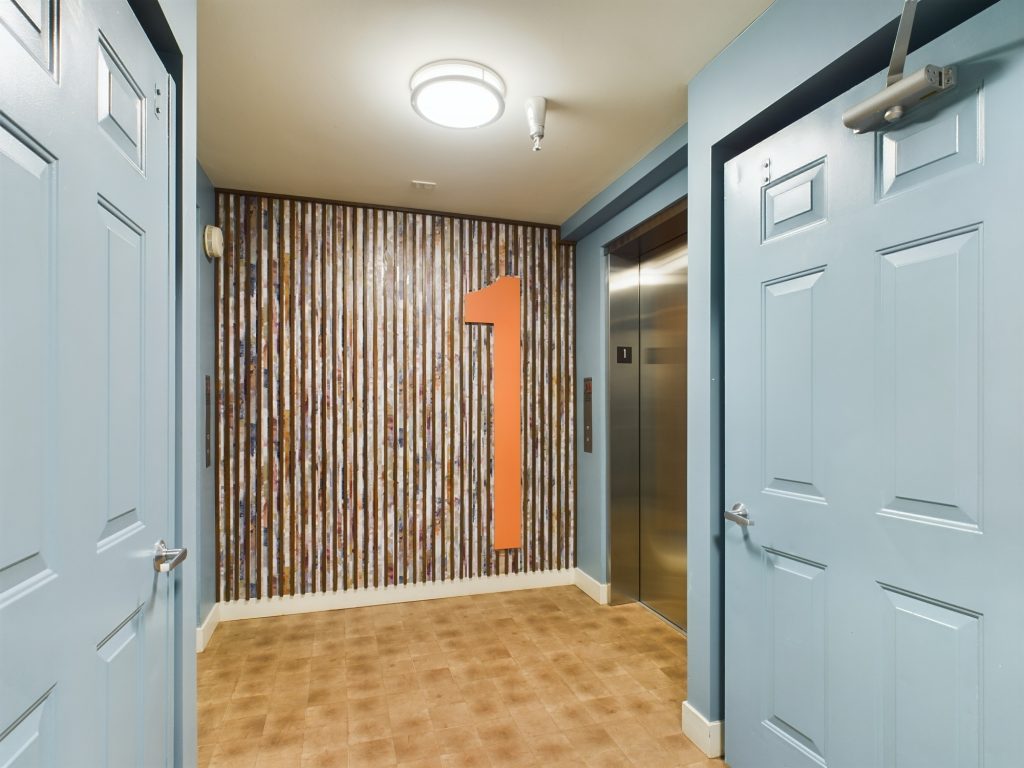 A hallway with blue doors and an orange door offering Apartments in Hollywood CA.