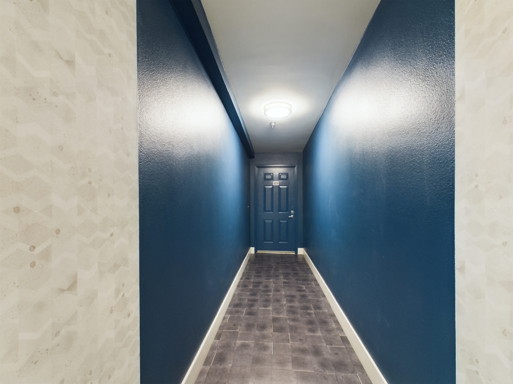 A hallway with blue walls and hardwood floors in Apartments for rent Hollywood CA.