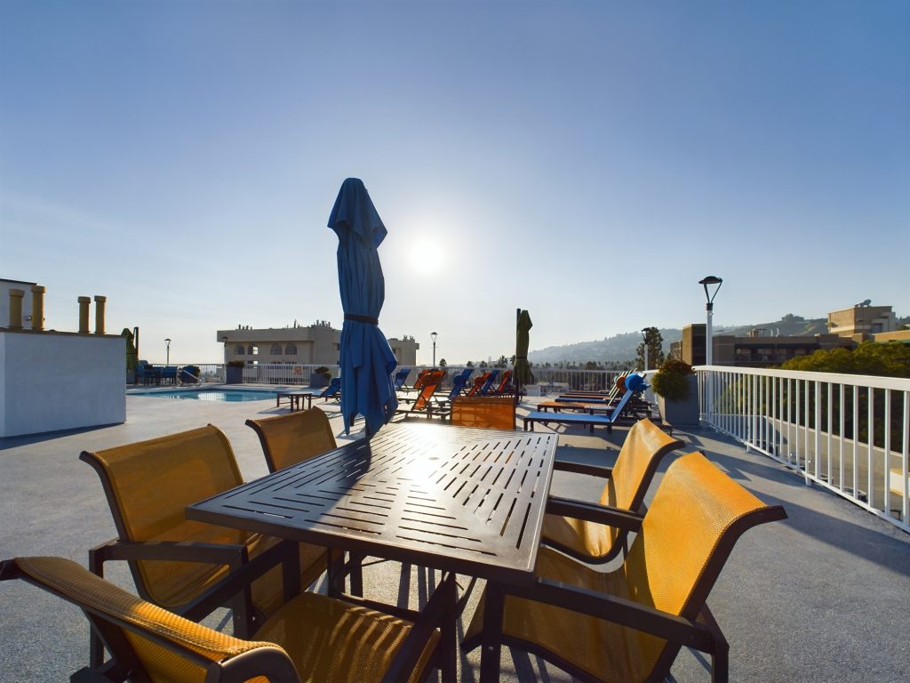 A rooftop furnished with a table and chairs, ideal for enjoying the panoramic views of Hollywood from these upscale apartments.