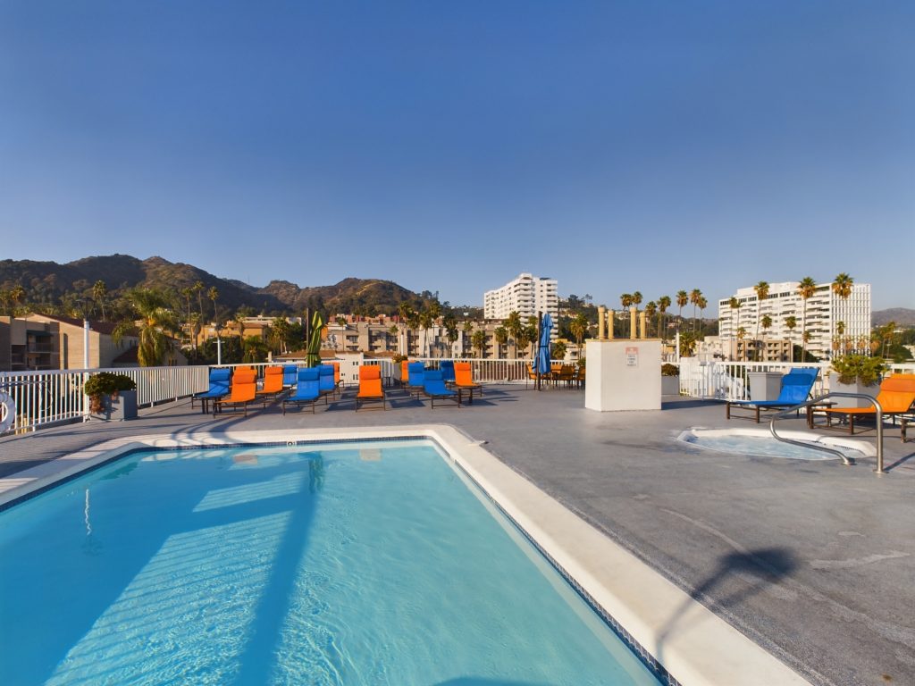 A rooftop pool with lounge chairs overlooking the picturesque mountains, available for residents in Hollywood CA apartments.