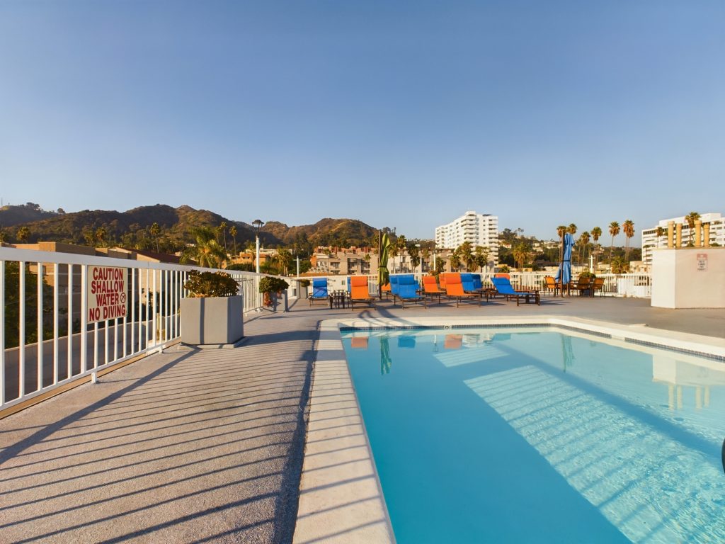 Apartments in Hollywood CA featuring a rooftop pool with lounge chairs, surrounded by breathtaking mountains in the background.