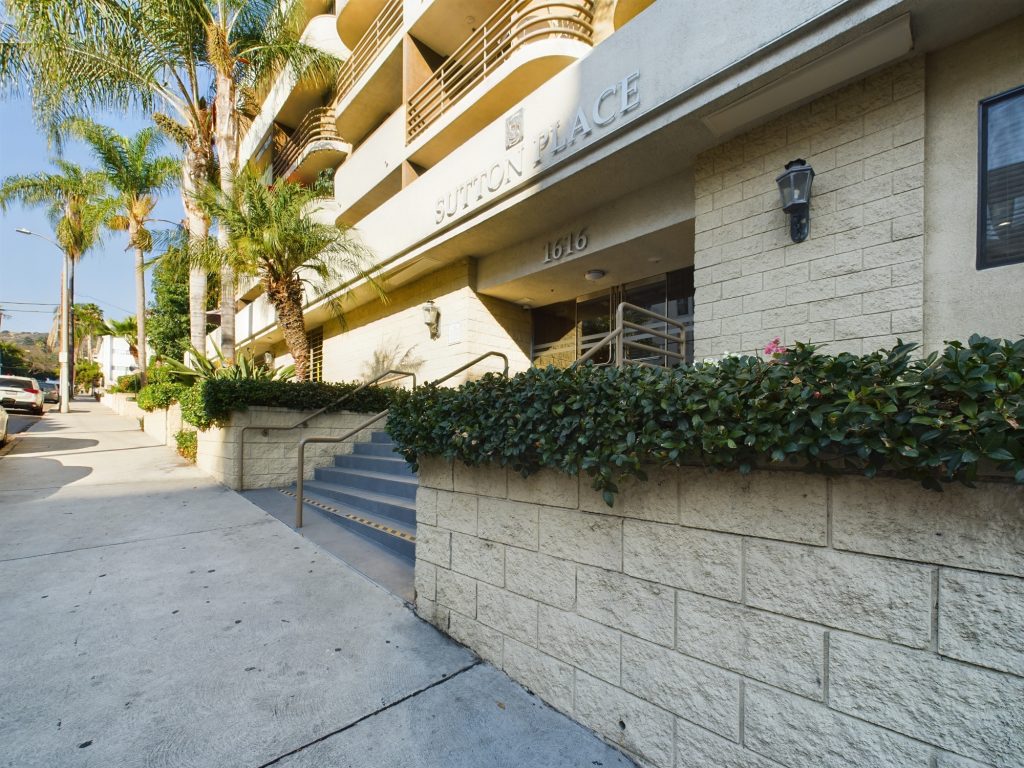 The entrance to an apartment building in Hollywood, CA with palm trees and bushes. Apartments in Hollywood CA + palm trees/bushes.